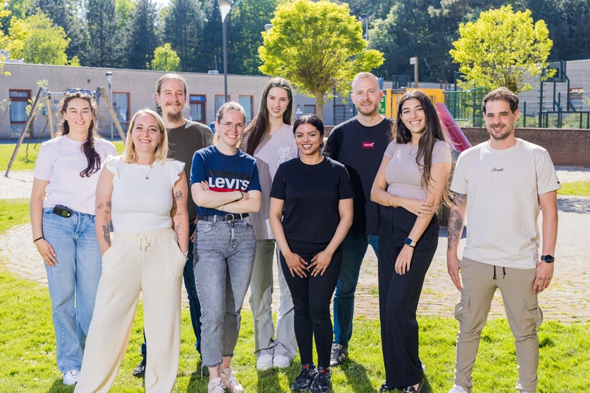 Groep van 9 collega's van Youz die staan buiten voor de kliniek in een groene omgeving.